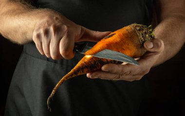 Kalori eklemek için pancarı bıçakla soymak. Mutfakta kırmızı pancarlı sebze yemeği hazırlamak için mütevazı bir konsept..