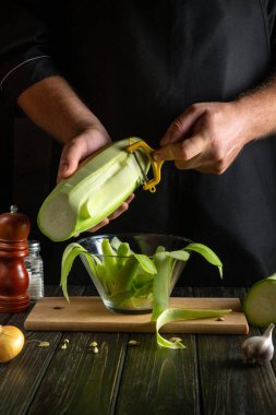 Kabak ve sebze soyacağı şefin ellerinde. Kahvaltı için mutfak masasında bir tabak kabak pişiriyorum..