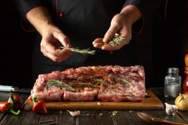 Biberiyeyi aroma ve tat için şefin elleriyle ekliyorum. Mutfak masasında baharat ve biberle kuzu biftek pişirme işlemi..