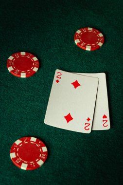 A pair of two diamonds lies on the green felt, surrounded by vibrant red poker chips, creating a tense atmosphere of anticipation and strategy at the card table. clipart