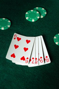 Bir el dolusu iskambil kâğıdı, diğer kartların arasında altılı ve dokuzlu kupa, yeşil poker fişleri ile çevrili, yeşil keçeli bir yüzey üzerinde, neşeli bir kart oyunu ima ediyor..