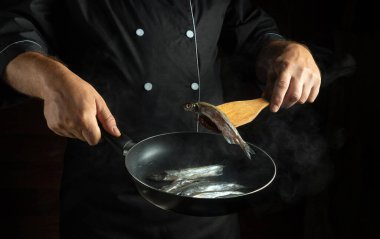 A skilled chef expertly flips fresh fish in a hot skillet, showcasing culinary techniques in a stylish kitchen. The steam and action create a vibrant cooking atmosphere. clipart