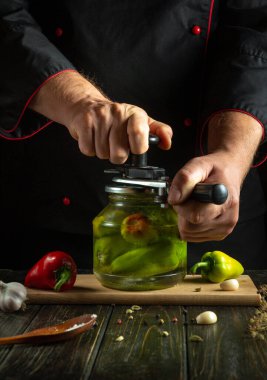 A skilled chef crafts homemade pickles, carefully pressing a lid onto a jar filled with vibrant peppers. The rustic kitchen ambiance enhances the artistic food preparation experience. clipart