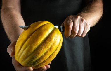 Yetenekli bir birey dikkatli bir şekilde parlak sarı bir karpuz oyuyor, kusursuz bir teknik ve sanatsal özellik sergiliyor. Arkaplan, sıkıca tutulan meyvenin karmaşık ayrıntılarına odaklanmamızı sağlar..