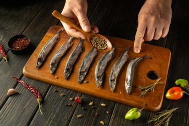 Taze tutulan balıklar tahtadan bir tahtanın üzerine yerleştirilir ve bir uzman onları tatlandırmaya hazırlanır. Sahneyi çevreleyen renkli baharatlar ve otlar aşçılık hazırlığının sanatını ön plana çıkarıyor..