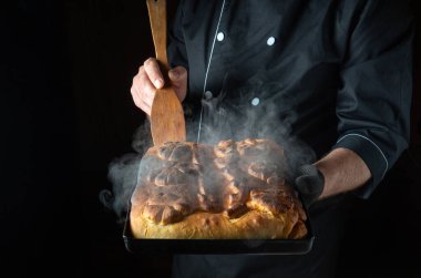 Fırıncı elinde taze pişmiş ekmek tepsisi tutar. Mutfak ışıklarının altında altın kabuğu parıldar. Aroması havayı doldurur, herkesi sıcaklığının tadını çıkarmaya davet eder..