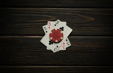 Üçlü ya da set kombinasyonuyla poker oyunu kazan. Poker kulübündeki siyah şarap masasında çip ve kartlar.