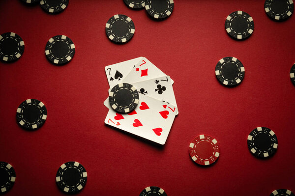 Four playing cards with a winning combination of four of a kind or quads are on a red table in a poker club. The concept of a successful game or expected victory.