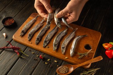 Bir çift el, tahta kesme tahtasından taze balık seçiyor..