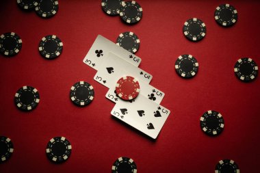 Poker kulübünde kırmızı masada iki çift ve siyah çipin kazanan kombinasyonuyla dört iskambil kağıdı yatıyor. Başarılı bir oyun ya da zafer konsepti.