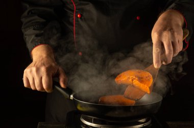 Sıcak bir mutfakta, bir şef parlak turuncu balkabağını ustalıkla cızırdayan bir tavada çevirir. Buhar yükselir, mutfak atmosferini yükseltir..