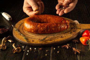 Ellerin marifetli sezonu ahşap bir kesme tahtasının üzerinde tütsülenmiş sosis, canlı baharatlar ve taze ürünlerle çevrili, mutfakta baştan çıkarıcı bir mutfak deneyimi yaratıyor..