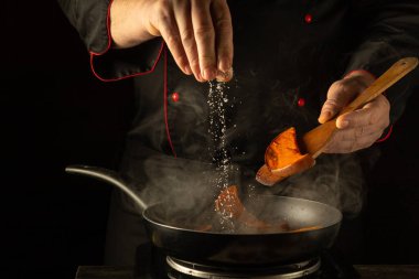 Tecrübeli bir şef kızartma tavasında cızırdayan kabağa bir tutam tuz ekler. Sıcak mutfak aromatik buharla dolu. Lezzetli yiyecekler vaad ediyor. Mutfak yeteneğini gösteriyor..
