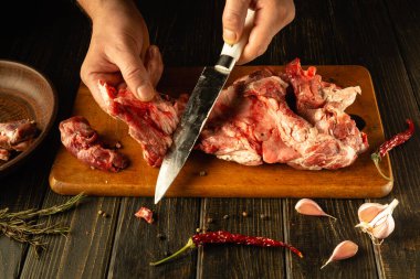 Ellerin ustalıkla bıçak kullanması, tahta bir tahtanın üzerinde taze kuzu eti dilimlemesi. Asya mutfağı.