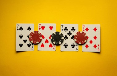Poker kartlarının dördünün kombinasyonu ya da dördüncünün fişleri sarı bir masada. Kumarhanede başarılı bir galibiyet kavramı.