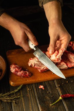 Eller, baharat ve otlarla çevrili, ahşap bir kesme tahtasındaki taze eti ustalıkla doğruyor, kırsal bir mutfakta sıcaklık ve geleneği çağrıştıran davetkar bir atmosfer yaratıyor..