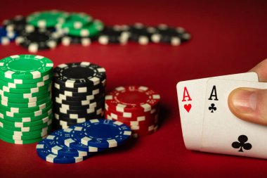 Oyuncu kırmızı poker masasında bir çift ya da iki as ile iskambil oynar. Klüpte ya da kumarhanede el ve çiplerin yakın plan çekimleri.