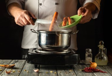 Becerikli bir şef, sıcak bir mutfak çalışma alanında renkli malzemeler ve baharatlarla çevrili, fırında kaynayan bir tencereye sosisleri ustalıkla atar. Sıcaklık ve mutfak yaratıcılığını çağrıştırır..