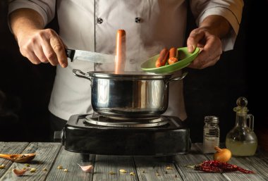 Tecrübeli bir şef buharda pişen bir tencereye ustalıkla sosis ekler. Mutfağın kırsal atmosferi sıcak ve davetkar bir mutfak deneyimini yansıtıyor. Her yemek aşığı için mükemmel..