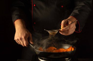 Yetenekli bir şef lezzetleri mükemmelleştirmeye odaklanır, baharatları cızırdayan bir tava altın-kahverengi sebze veya kabağa serpmeye. Buhar yükselir, zarif bir mutfakta aşçılık deneyimini geliştirir..