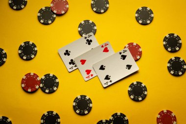 Üçlü poker kombinasyonlu birkaç kart ya da sarı bir masanın üzerinde, çiplerle çevrili bir şekilde yatıyorlar. Atmosfer başarılı bir şekilde heyecan ve poker stratejisi kazanmakla suçlanıyor..