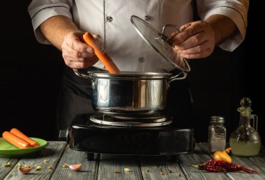 Yetenekli bir aşçı taze sosisleri bir tencere kaynar suya daldırmaya hazırlanır. Köy mutfağı, yemek elementlerinin yumuşak parıltısıyla karanlık bir zemine karşı sıcaklık yayar..