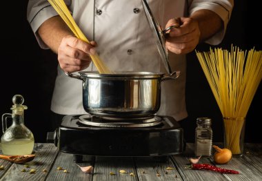 Yetenekli bir aşçı spagetti tellerini kaynatmaya hazırlanırken ustalıkla tutar. Mutfak taze otlar ve baharatlarla süslenmiş. Mutfak yaratıcılığı için davetkar bir atmosfer yaratıyor..