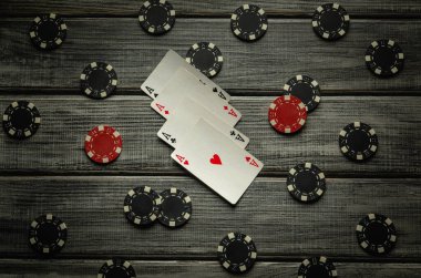 Dört as yıpranmış ahşap bir masada yatıyor, bir sürü renkli poker fişi tarafından çerçevelenmiş. Ortam gergin, loş bir alanda oynanan yüksek bahisli oyunların heyecanı ortaya çıkıyor..