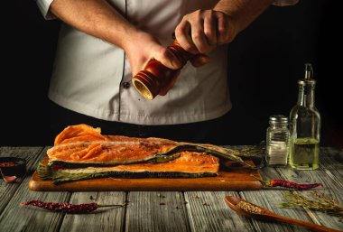 Becerikli bir şef, somon filetosuna bol miktarda taze kırılmış biber ekleyip, sıcak, kırsal bir mutfakta tadını arttırır. Çeşitli baharatlar ve yağlar ahşap masada ustalıkla düzenlenir..