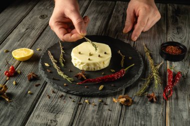 Eller, kaymak tabaktaki krem peynirin etrafına taze otlar ve baharatlar dizer. Parlak limon bu mutfak icadına renk ve tazelik katar..