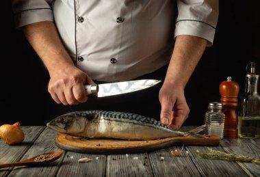 Şef mutfakta uskumru ya da scomber pişirir. Restoran ya da otel için balık yemi pişirme kavramı. Balık aşçısının elindeki bıçak..