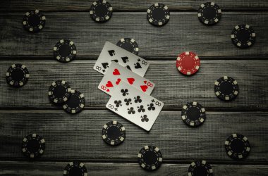 Heyecan verici bir poker oyunu, kırsal ahşap bir masanın üzerinde sergileniyor, üç çeşit veya set kombinasyonu ve çeşitli poker çipleri, oyuncular için gergin bir atmosfer yaratıyor..