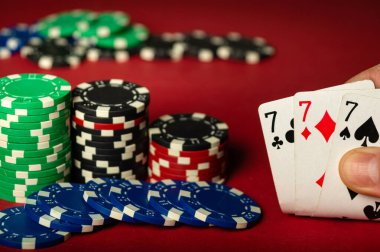 Oyuncuların el ele tutuştuğu kağıt oyunlarında üçlünün kombinasyonu ya da kırmızı poker masasında oynanır. Kulüpteki masada kart ve çiplerin yakın plan çekimleri.