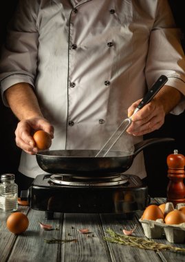 Sıcak bir mutfakta, yetenekli bir şef taze bir yumurta tutar ve ustalıkla onu sıcak bir tavaya kırar. İnce buhar yükselişi, bileşenler dönüşümlerini beklerken davetkar bir atmosfer yaratıyor..