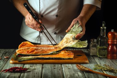 Aşçı mutfak masasında kırmızı somon balığı filetosu hazırlıyor. Pembe somon balığı ve otelde yemek pişirmek için lezzetli balık..