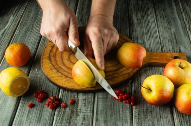 Elleri ustalıkla bir elmayı keserken canlı meyveler kırsal bir tahtanın etrafını sarıyor. Deniz aygırı ve böğürtlenler renk katar, sıcak öğleden sonra ışığında canlı ve davetkar bir mutfak atmosferi yaratır..