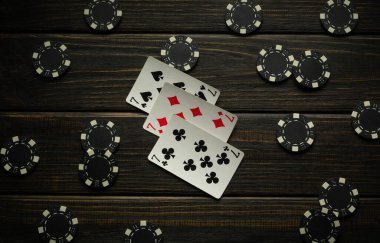 Siyah poker fişleri ile çevrili siyah bir tahta masanın üzerinde oyun kartları vardı. Oyuncular yoğun bir oyuna girerken atmosfer beklenti ve stratejiyle doludur..