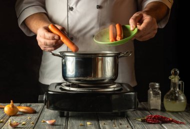 Sıcak bir mutfakta, bir şef taze sebze ve baharatla çevrili bir tencereye ustalıkla sosis ekler ve enfes bir yemek yaratır. Atmosfer davetkar ve aromatik..