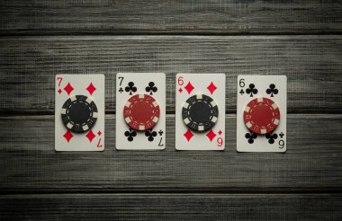 Playing cards, two pairs, are laid out in a row on a rustic wooden table, reflecting the excitement of a high-stakes poker game. The light casts soft shadows, adding to the atmosphere of anticipation. clipart