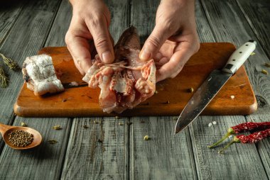 Eller çiğ et balıklarını ustalıkla idare eder. Sıcak, kırsal bir mutfakta aşçılık becerileri sergiler. Ahşap kesim tahtası, bıçak ve baharatlar yemek meraklıları için davetkar bir ortam yaratır..