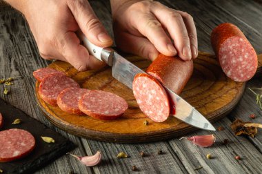 Eller yuvarlak ahşap bir tahtanın üzerinde dikkatlice kesilmiş eti, lezzetli bir şekilde düzenlenmiş dilimler ve dağınık baharatlarla, kırsal mutfak atmosferini geliştiren.