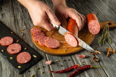 Sıcak bir mutfakta ahşap bir tahtanın üzerinde ustalıkla pişirilmiş etleri kesiyorlar. Etlerin canlı renkleri ve baharatlarla çevrili dokuları üzerinde yoğunlaşıyoruz..