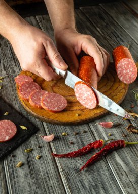 Köy tahtasında ustalıkla et dilimleyen bir insan. Acı biber ve sarımsak gibi baharatlar ortama renk katar, aşçılık sanatının özünü yakalar..