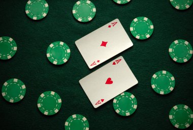 İki iskambil kartı yeşil bir keçeli masaya yerleştirilmiş kalp ve elmas asları gösteriyor. Birkaç poker fişi ile çevrili. Arkadaşlarla kart oynamak için davetkar bir ortam yaratıyor..