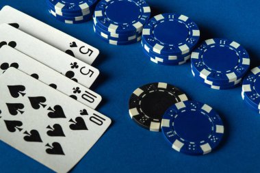 Mavi masada kazanan iki çift ve düzgünce istiflenmiş mavi poker çipleriyle kağıt oynayarak heyecan verici bir atmosfer yaratıyorlar..