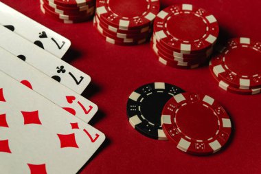 Dağınık iskambil kağıtları ve kırmızı bir masada renkli poker fişleri ile eğlenceli bir oyun akşamı. Kazanan kombinasyonlu bir kumar oyunu..
