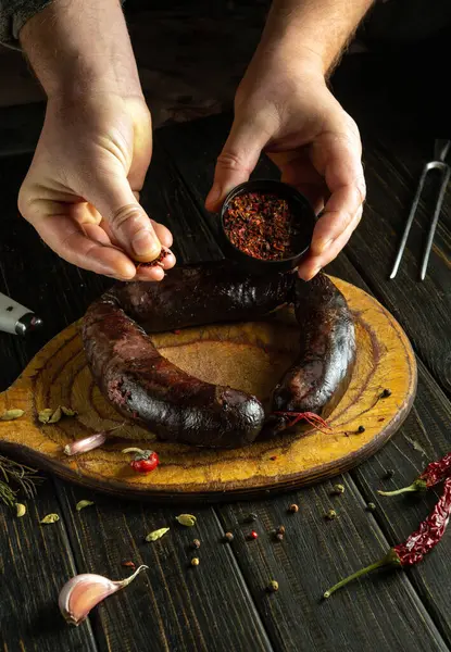 Fırında pişmiş kan sosisine elle baharat ekliyorum. Latin Amerika ulusal yemeği mutfak masasında aromatik baharatlarla hazırlandı..