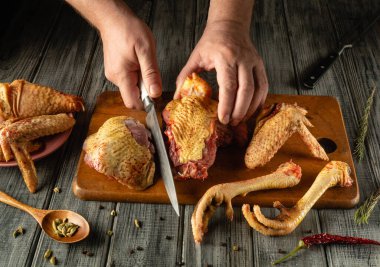 Doğal ışıkla dolu rahat bir mutfakta baharat ve otlarla çevrili ahşap bir tahtanın üzerinde ustalıkla kesilmiş çiğ kümes hayvanları..