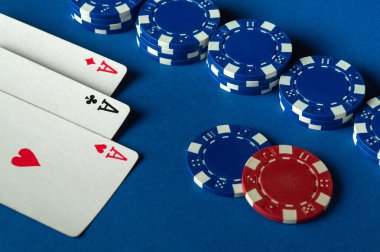 Heyecan verici bir kart oyunu atmosferi. Üç as ve mavi poker fişleri bir gece boyunca açık mavi bir masada toplanıyor..