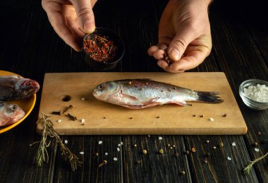 Tahta kesme tahtasının üzerinde taze balık hazırlarken görüldü. Diğer malzemeler yakınlarda dinlenirken, baharatlar ve bitkiler üzerine serpiliyor. Ortam samimi ve davetkar..